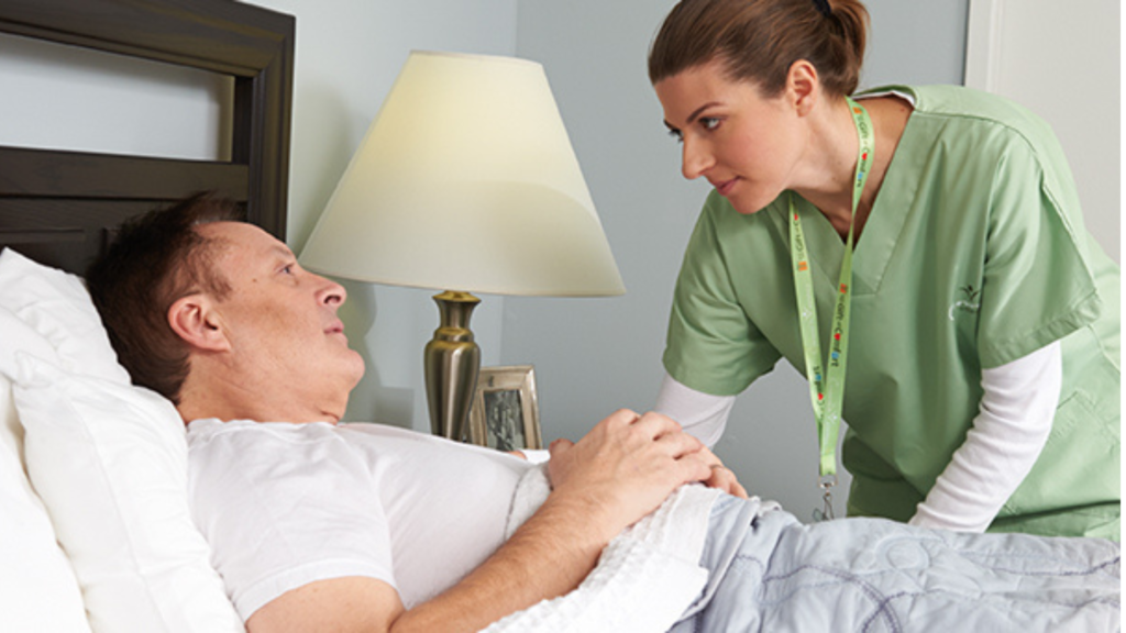 A Man with a Terminal illness Lying in Bed being attended to by a Nurse Aid